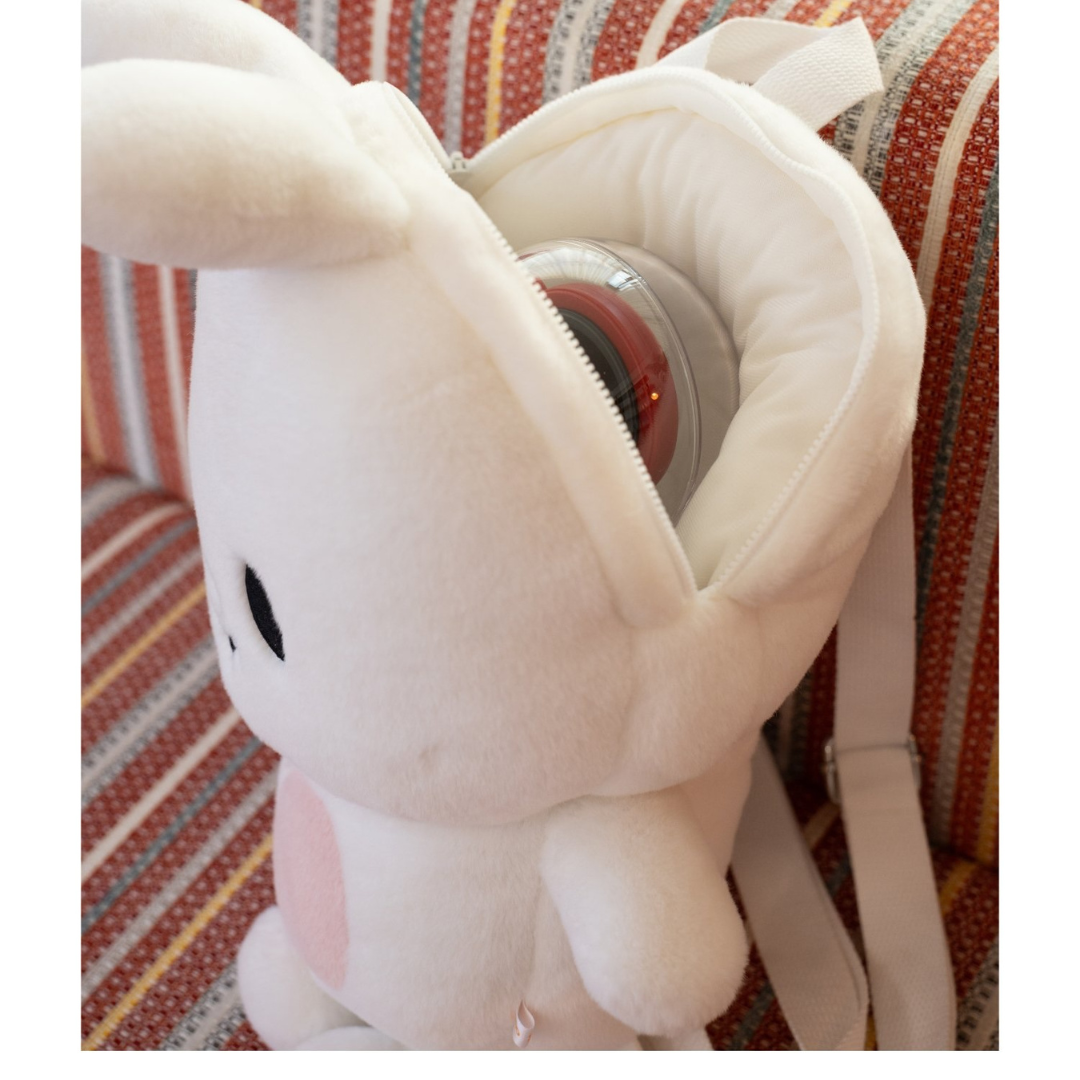 Leebit plush backpack with its zip compartment open and an example item inside